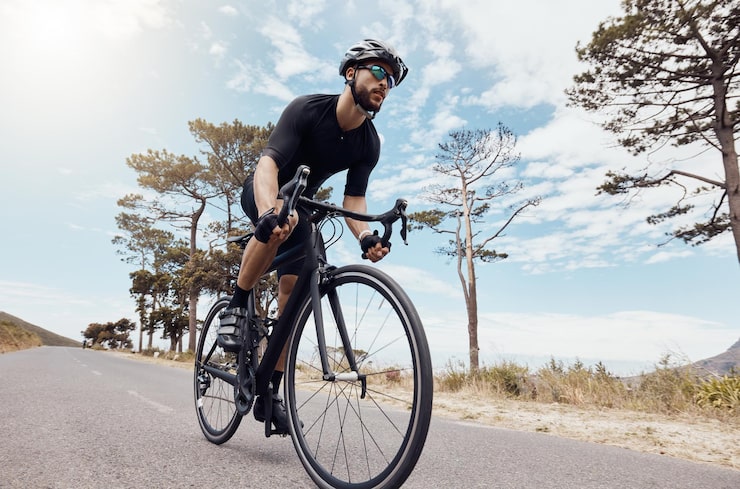 A road cyclist training on a long asphalt highway, demonstrating the endurance needed for Olympic road cycling distances. A road cyclist training on a long asphalt highway, demonstrating the endurance needed for Olympic road cycling distances.